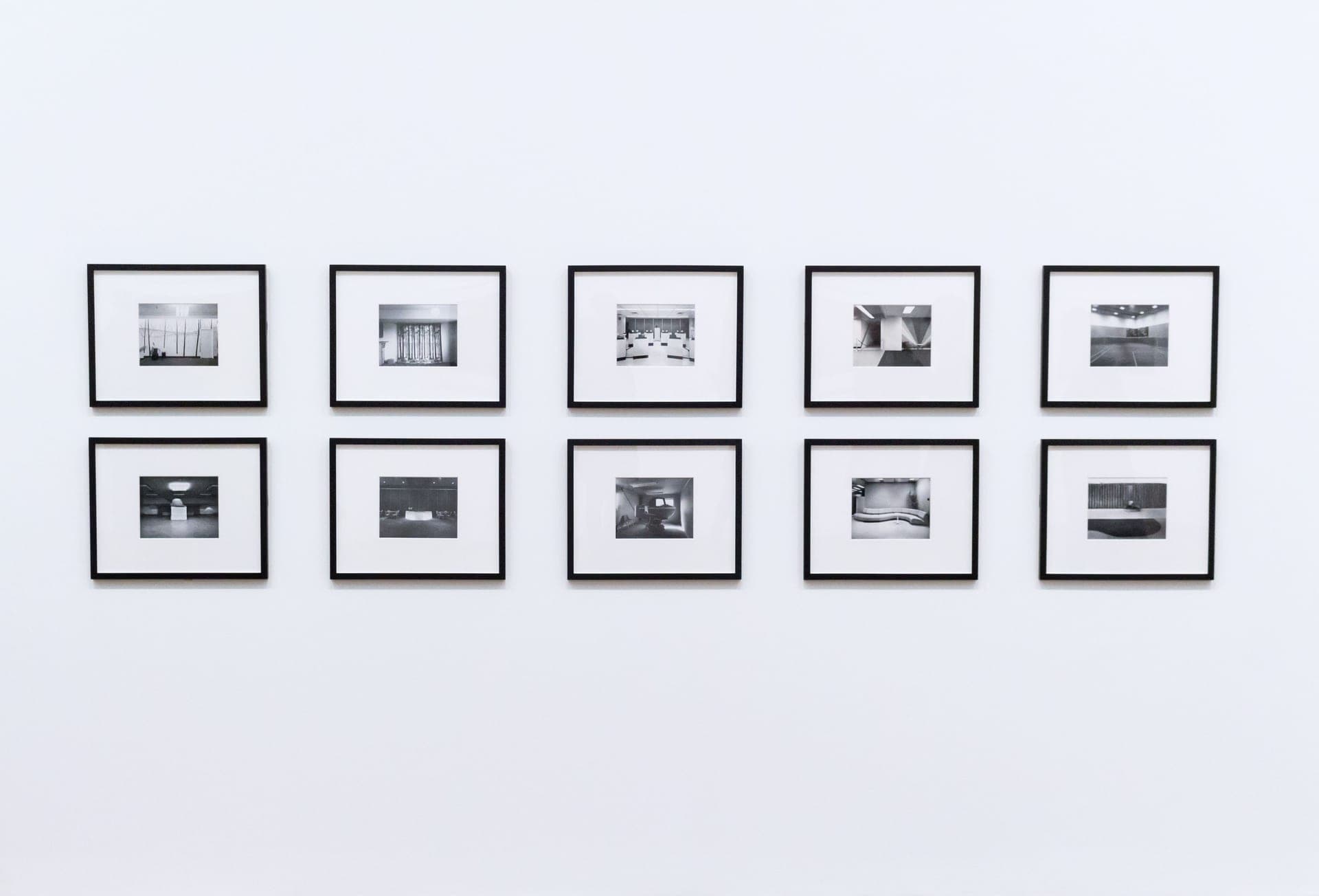 Assorted wooden and black picture frames stacked against a wall